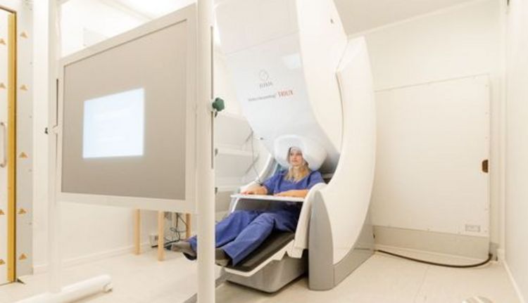 Junge Frau sitzt im Magnetoenzephalographie-Scanner.