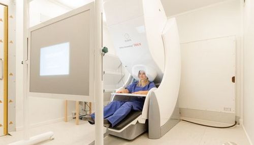 Junge Frau sitzt im Magnetoenzephalographie-Scanner.