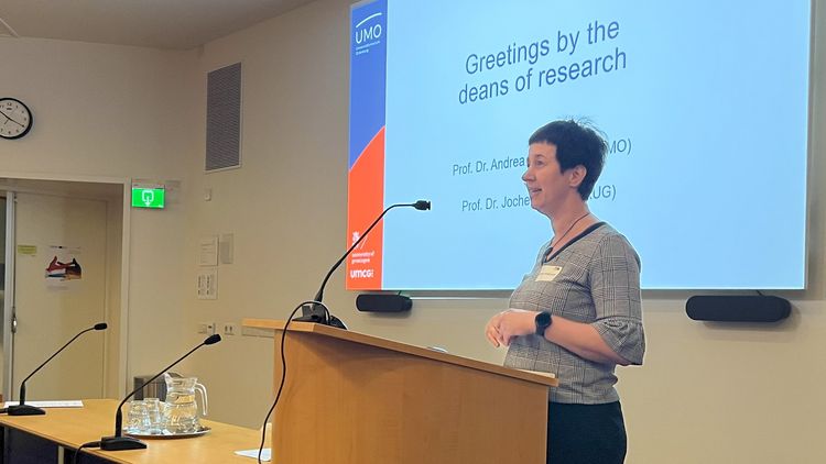 Andrea Hildebrandt referiert und steht an einem Pult mit Mikrofon.