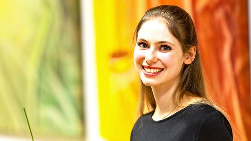 Porträt von Maya Sophie de Wilde mit Urkunde und Blumenstrauß.