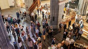 Viele Menschen stehen in einer Kirche und unterhalten sich.