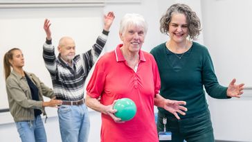 Tania Zieschang assistiert einer Teilnehmerin, die einen Ball in der Hand hält, bei einer Übung.