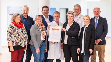 Die Genannten posieren mit dem Zertifikat.