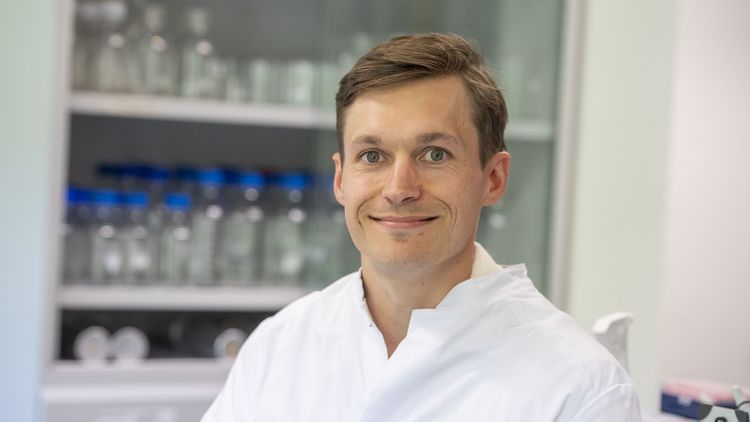 Porträt von Volker Kinast im Kittel im Büro.