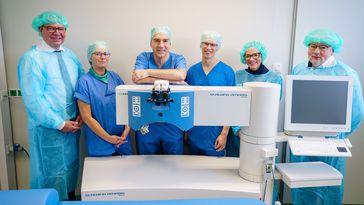 Die genannten Personen stehen in OP-Kleidung hinter dem medizinischen Gerät. Neben dem schwenkbaren Laserarm ist ein mit dem Gerät verbundener Computer zu erkennen.