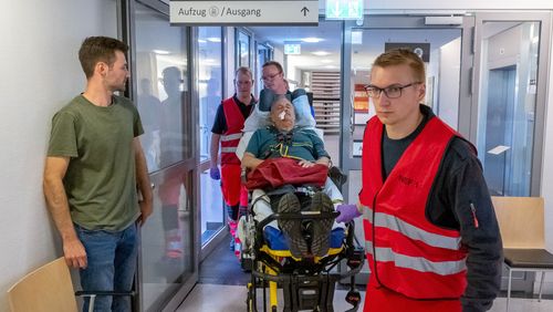 Notfallsanitäter schieben einen Mann auf einer Trage durch einen Krankenhausflur.
