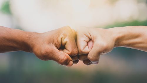 Die Fäuste zweier Menschen berühren sich.