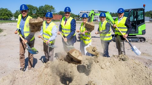 Menschen mit Spaten werfen Sand.