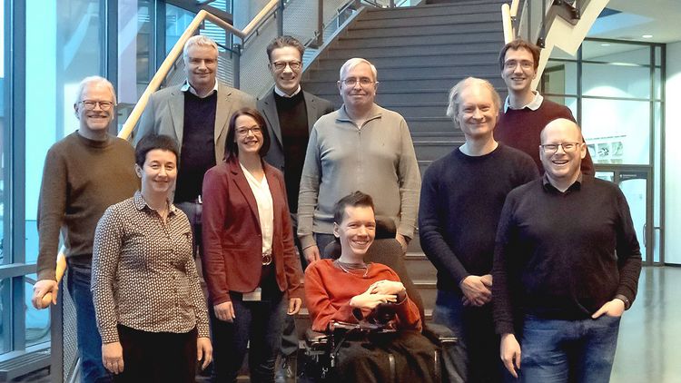 Zwölf Menschen stehen nebeneinander auf einer Treppe.