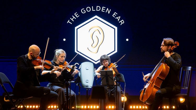 Streichquartett mit zwei Männern und Frauen vor einer Leinwand, auf der "The Golden Ear" steht.